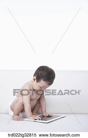A baby looking at the tablet PC on the couch View Large Photo Image Stock Photography - A baby looking at the tablet PC on the couch. Fotosearch