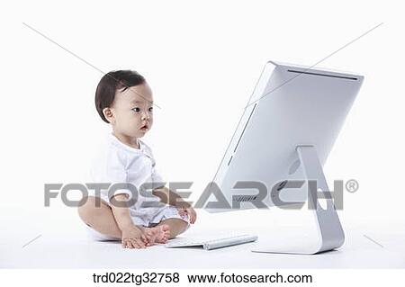 A baby sitting with a computer View Large Photo Image Stock Photo - A baby sitting with a computer. Fotosearch