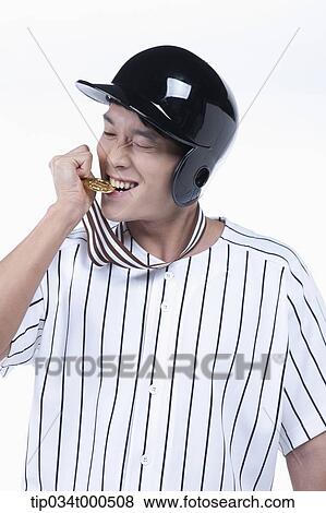 Stock Photo - A baseball player biting gold medal. Fotosearch