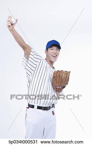 Stock Image - A baseball player holding up a ball. Fotosearch
