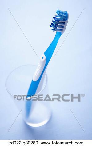 Stock Image - A blue tooth brush in a plastic cup . Fotosearch