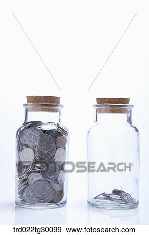 Stock Photo - A bottle full of coins and another bottle being empty . Fotosearch