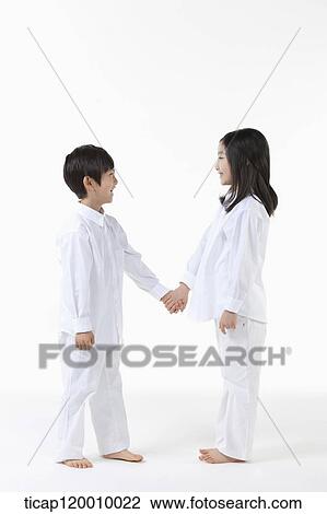Stock Image - A boy and girl facing each other with holding hands. Fotosearch