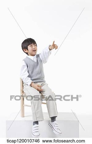 Stock Photograph - A boy pointing to the sky on the chair. Fotosearch
