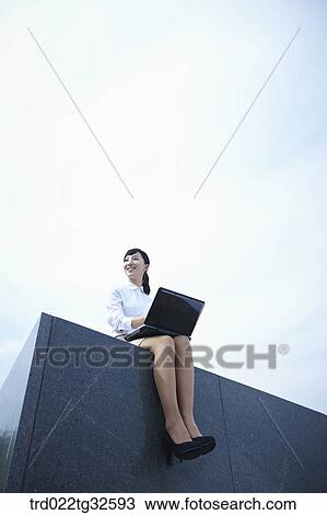 Stock Image - A business woman sitting with the laptop. Fotosearch