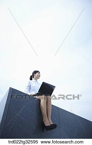 Stock Photography - A business woman sitting with the laptop. Fotosearch
