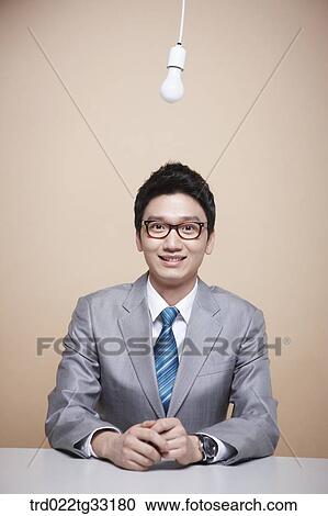 Stock Image - A businessman and a white light bulb. Fotosearch