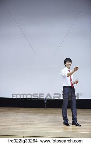 Picture - A businessman having presentation on the stage. Fotosearch