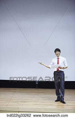 Stock Image - A businessman having presentation on the stage. Fotosearch