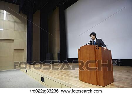 Stock Photograph - A businessman having presentation on the stage. Fotosearch