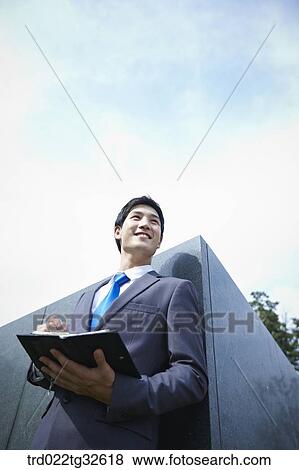 Stock Photo - A businessman holding a pen and planner. Fotosearch
