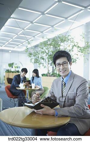 A businessman holding a planner in the lounge View Large Photo Image Picture - A businessman holding a planner in the lounge. Fotosearch