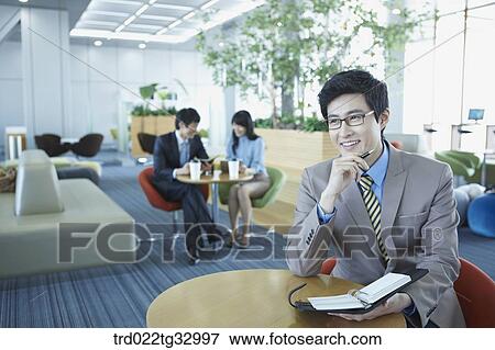 A businessman holding a planner in the lounge View Large Photo Image Stock Photo - A businessman holding a planner in the lounge. Fotosearch