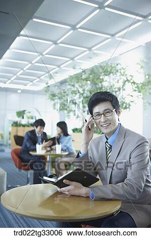 A businessman holding a planner in the lounge View Large Photo Image Stock Photograph - A businessman holding a planner in the lounge. Fotosearch