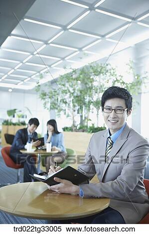Stock Photography - A businessman holding a planner in the lounge. Fotosearch