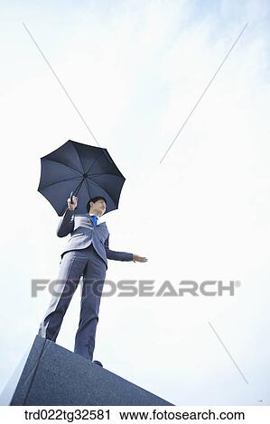 Stock Image - A businessman holding an umbrella. Fotosearch