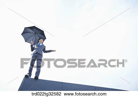 Stock Image - A businessman holding an umbrella. Fotosearch