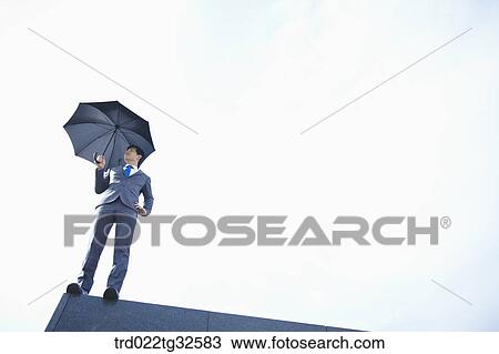 A businessman holding an umbrella View Large Photo Image Stock Image - A businessman holding an umbrella. Fotosearch