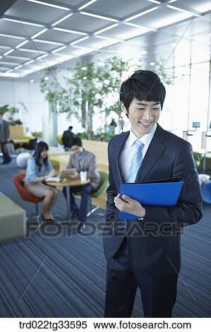 Stock Photography - A businessman holding the document in the lounge. Fotosearch