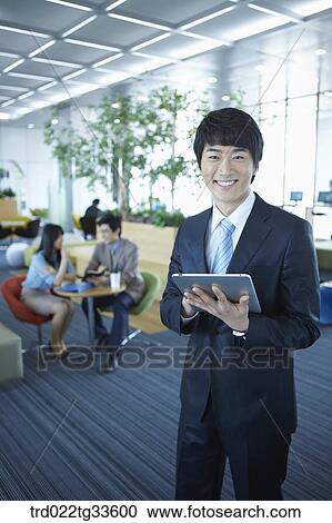 Stock Image - A businessman holding the tablet PC. Fotosearch
