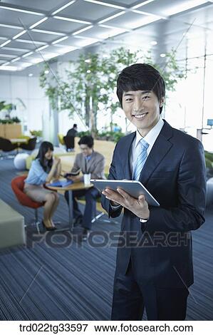 Stock Photo - A businessman holding the tablet PC. Fotosearch
