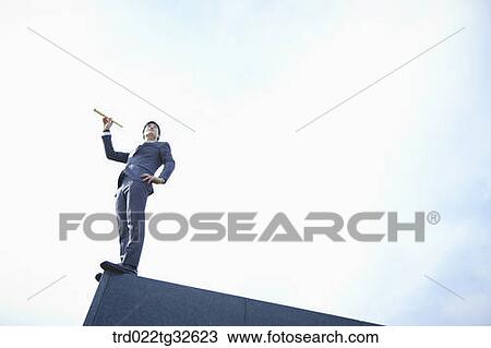 Stock Image - A businessman holding the telescope. Fotosearch