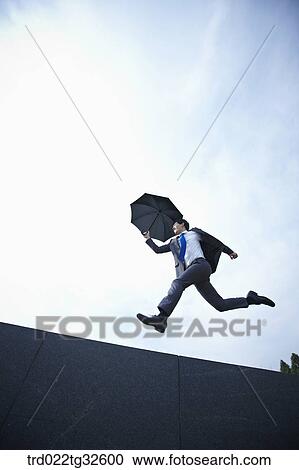 A businessman jumping with the umbrella View Large Photo Image Stock Image - A businessman jumping with the umbrella. Fotosearch