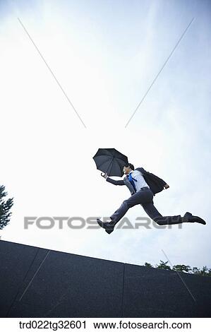 A businessman jumping with the umbrella View Large Photo Image Stock Image - A businessman jumping with the umbrella. Fotosearch