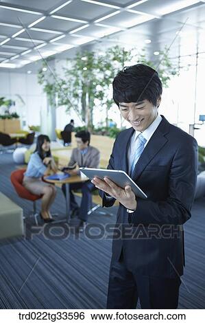 Stock Photograph - A businessman looking at the tablet PC . Fotosearch