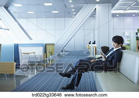 Stock Photograph - A businessman looking at the tablet PC . Fotosearch