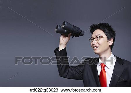 Stock Image - A businessman looking through the binoculars. Fotosearch
