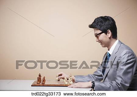 Stock Image - A businessman playing chess game. Fotosearch