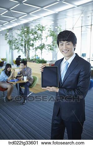 Stock Image - A businessman presenting the tablet PC. Fotosearch