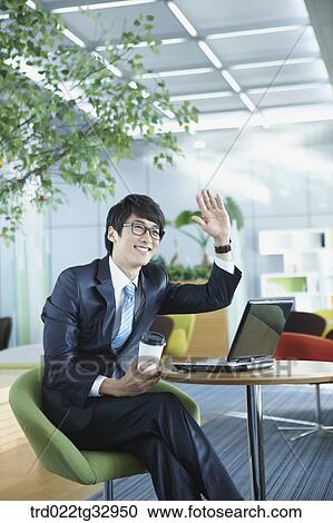 Stock Image - A businessman saying hello in the lounge. Fotosearch