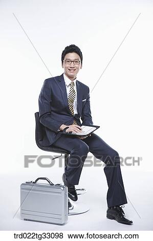 A businessman sitting with a planner and suitcase View Large Photo Image Stock Photo - A businessman sitting with a planner and suitcase. Fotosearch