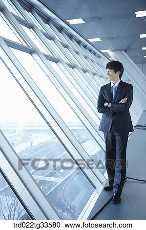 A businessman standing by the window View Large Photo Image Stock Image - A businessman standing by the window. Fotosearch