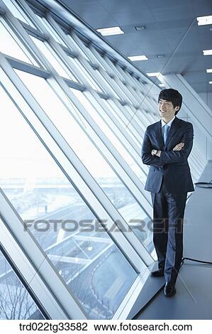 A businessman standing by the window View Large Photo Image Stock Image - A businessman standing by the window. Fotosearch
