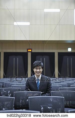 Stock Photo - A businessman taking a note in the auditorium. Fotosearch
