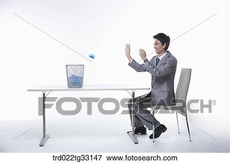 Stock Photo - A businessman throwing the paper into the waste basket. Fotosearch