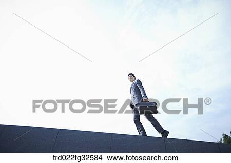 Picture - A businessman walking with the briefcase. Fotosearch