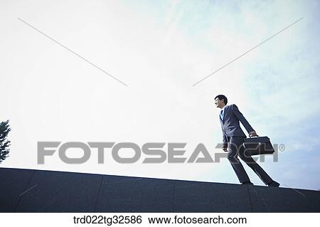 A businessman walking with the briefcase View Large Photo Image Stock Photograph - A businessman walking with the briefcase. Fotosearch
