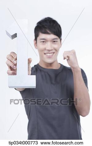 Stock Image - A cheerful man holding the number one. Fotosearch