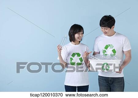 Stock Image - A couple smiling with recycling bin . Fotosearch