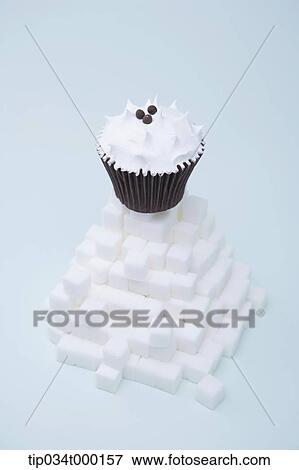Stock Photo - A cup cake on the pile of cube sugar. Fotosearch