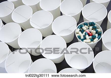 Stock Image - A cup full of tablets with other paper cups empty. Fotosearch