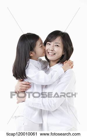 Stock Image - A daughter kissing on mother's cheek. Fotosearch