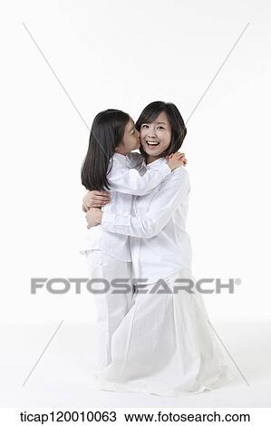 Stock Image - A daughter kissing on mother's cheek. Fotosearch