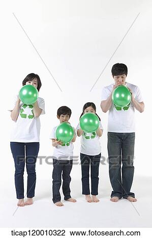 Stock Image - A family blowing green balloons . Fotosearch