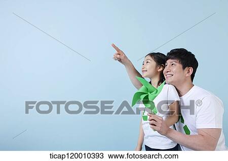 Stock Image - A father and daughter with a green pinwheel. Fotosearch