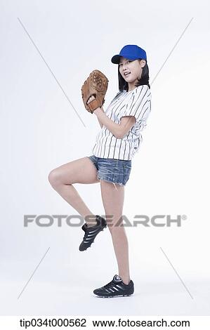Stock Image - A female baseball player pitching a ball. Fotosearch